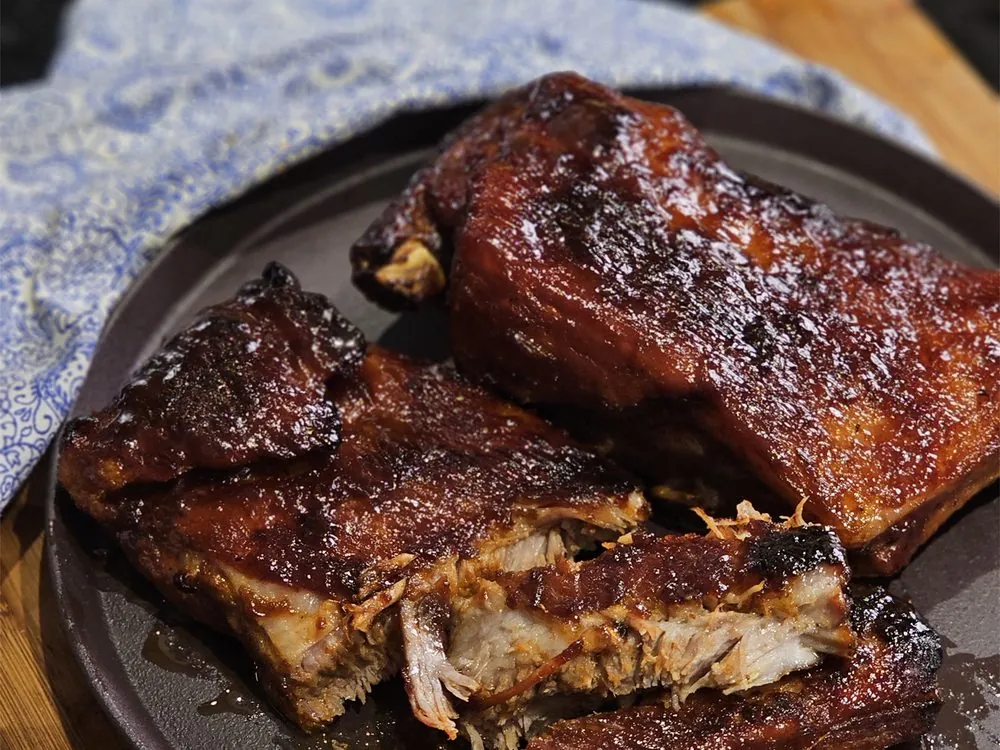 Costelinha com molho barbecue caramelizada, desfiando, em prato escuro