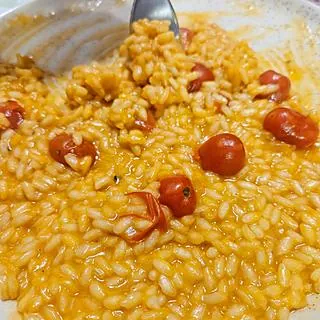 Risoto de tomate alaranjado com tomates-cereja inteiros, feito por Kito Carneiro