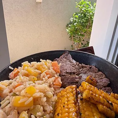 Arroz com legumes e milho grelhado ao lado de bife, feito por Luisa Balaniuc