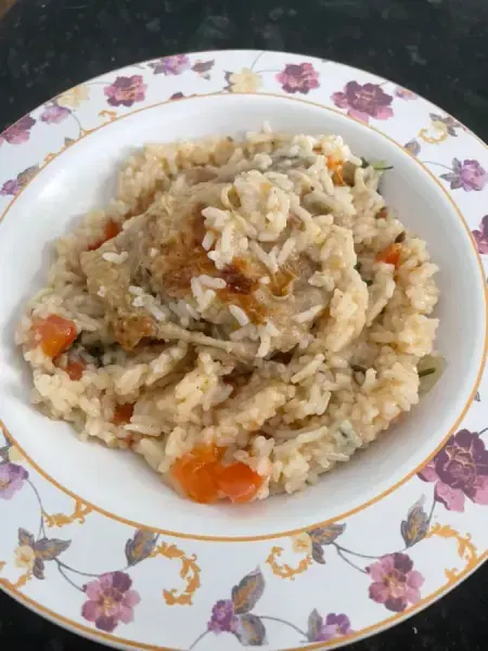 Arroz cremoso com cubos de cenoura em prato branco de borda floral, feito por Larissa Conti