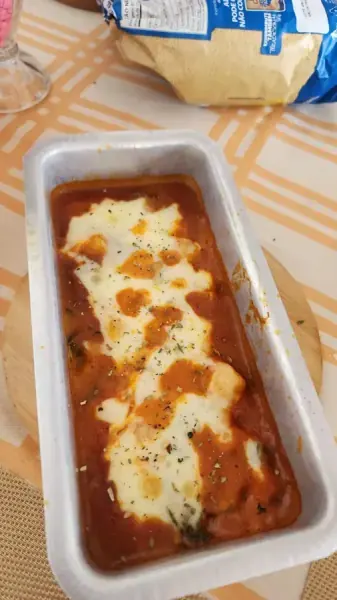 Forma de alumínio com molho de tomate e muçarela derretida, feita por Cass Brandão