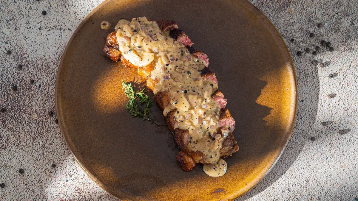 Bife com molho cremoso de pimenta e tomilho em prato ocre