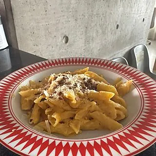 Mac and cheese de penne com queijo ralado em prato de borda vermelha, feito por Marjory Hirata