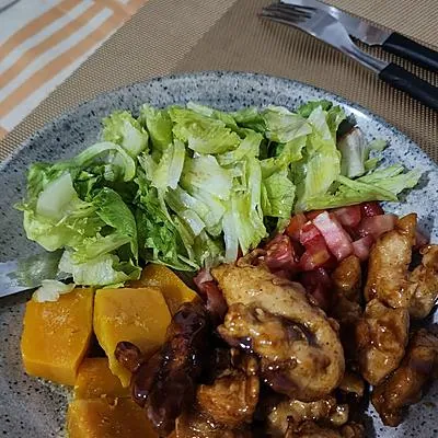 Pedaços de frango ao mel com salada de alface, abóbora e tomate em prato cinza, feito por Cass Brandão